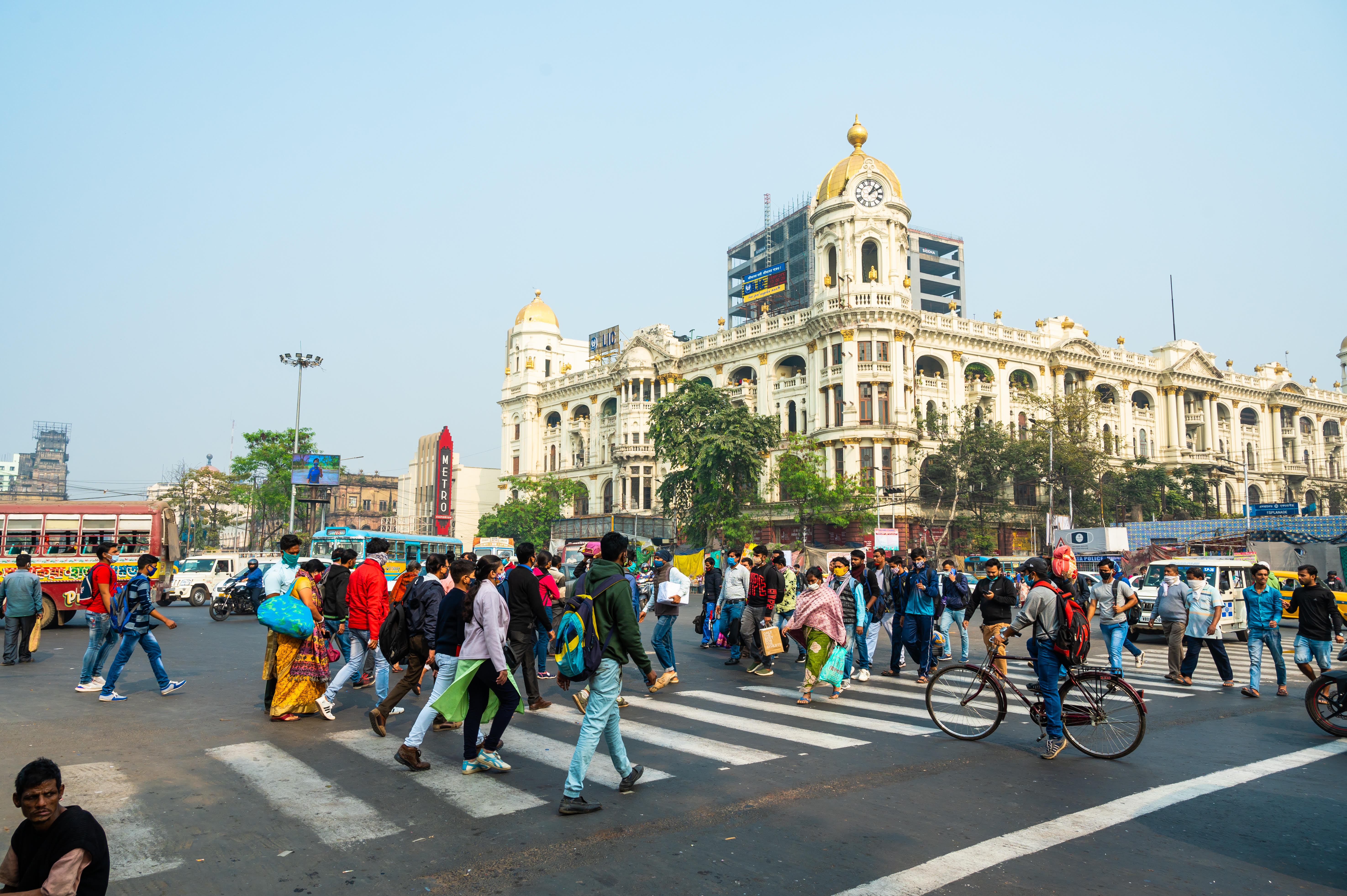 Busy street in INdia filled with cars and people crossing the road